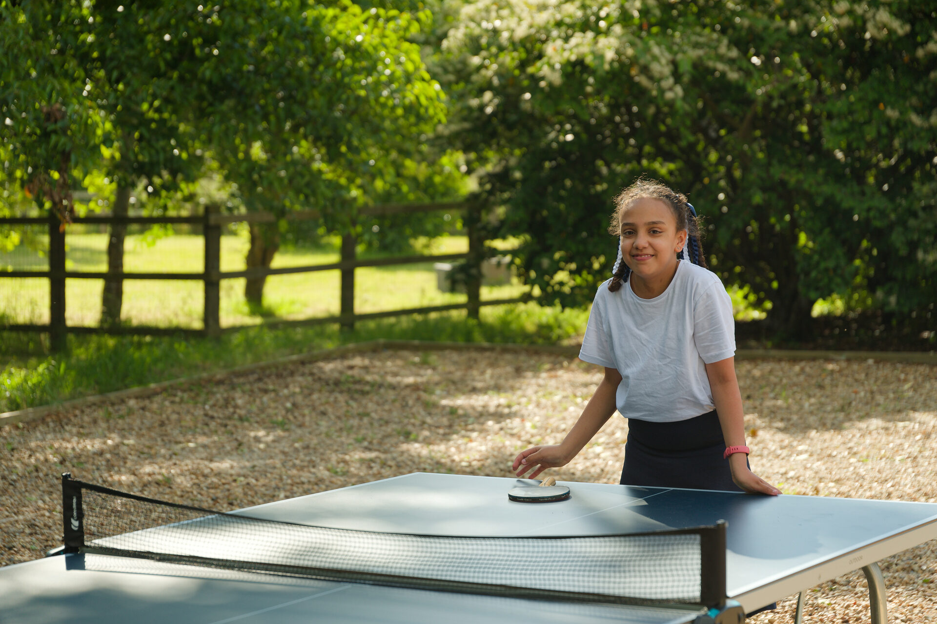 A student rests her hands on a table tennis table. 